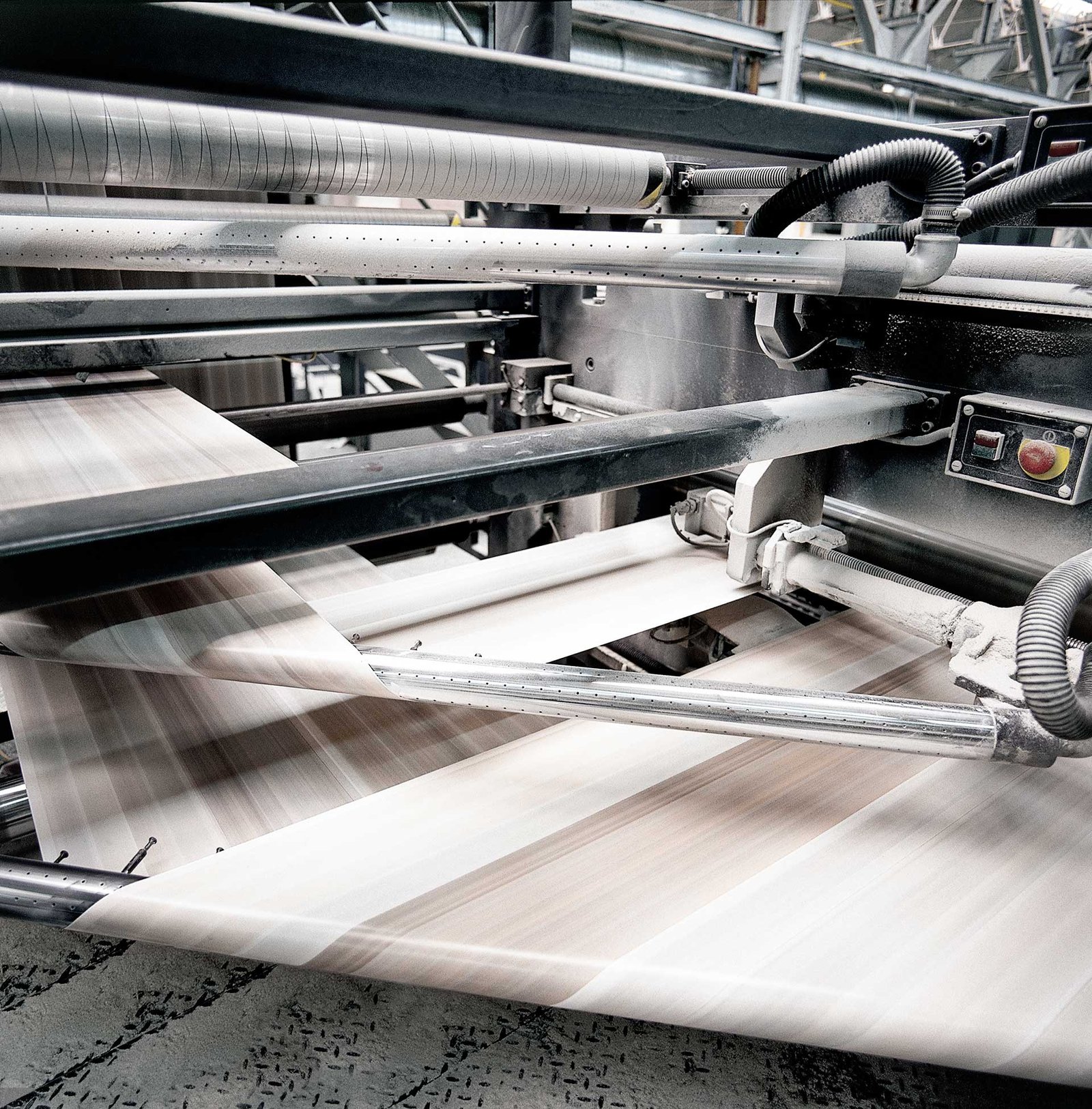 A professional Print Production Director inspecting an offset print sheet at a printing facility.