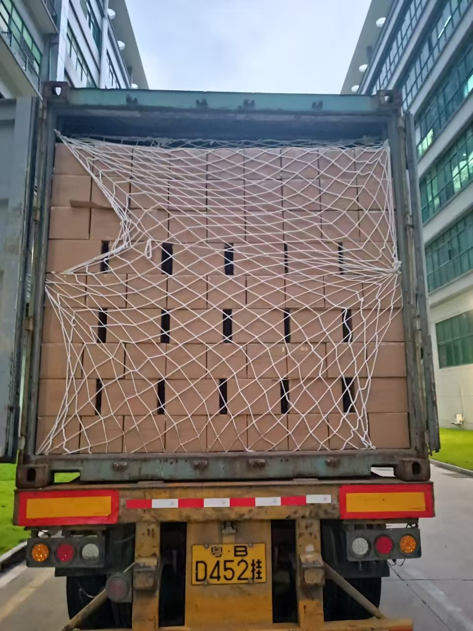 A shipping container being loaded at a port with boxes of books