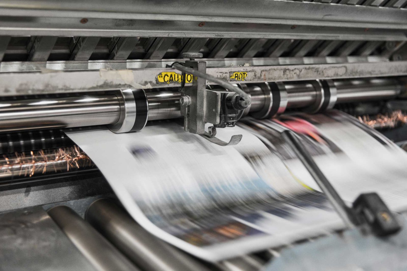 A split image showing a designer's screen on one side and a running printing press on the other